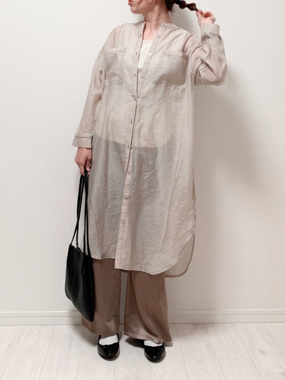 ベージュ系のシャツワンピース、ブラウン系のパンツ、ホワイト系のタンクトップを着用したレディースの春コーディネートの1枚目の写真