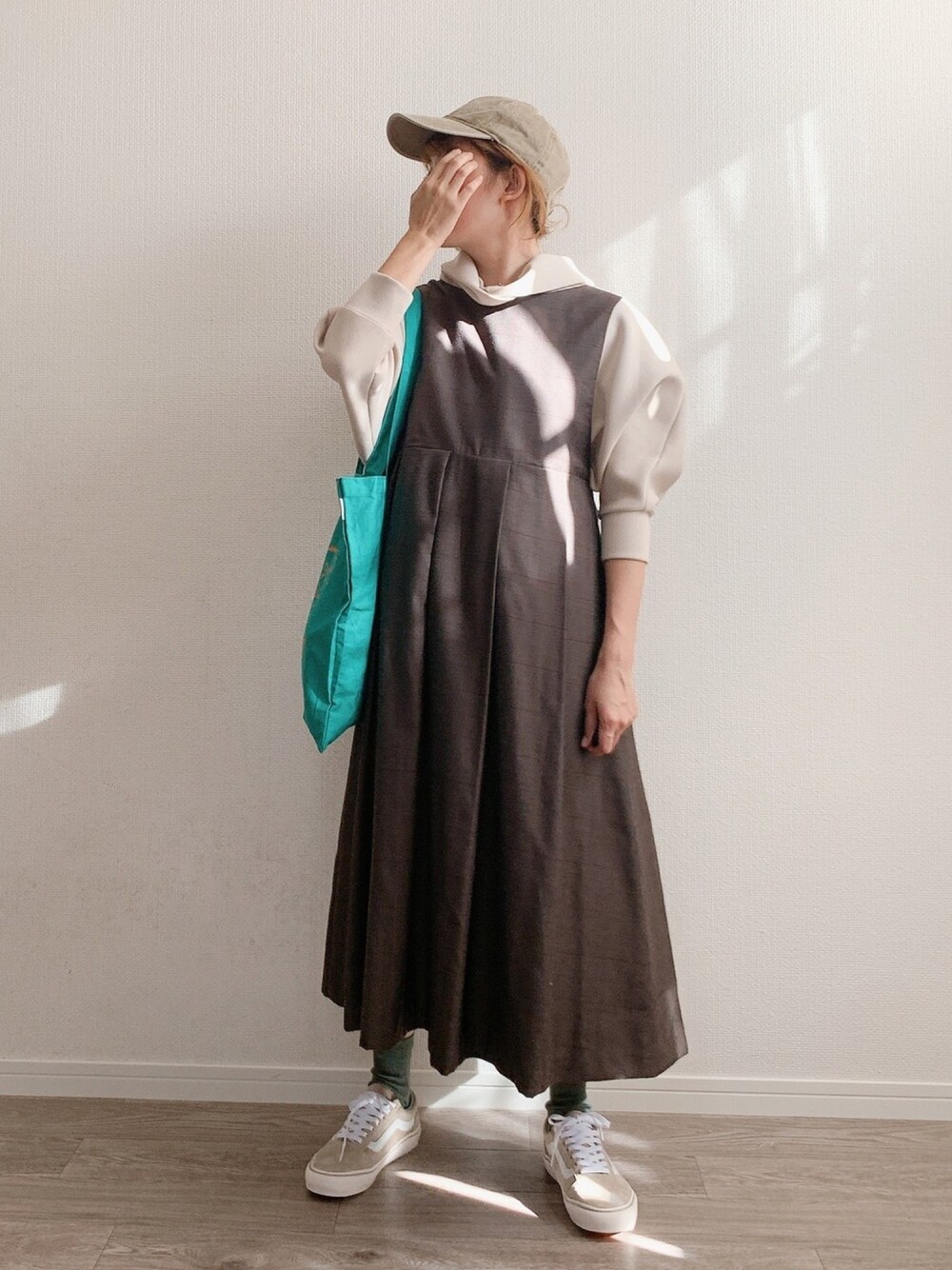 ベージュ系のパーカー、ブラウン系のワンピース、グリーン系のトートバッグを着用したレディースの秋コーディネートの1枚目の写真