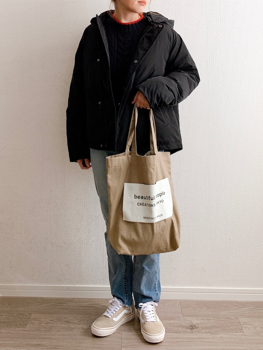 ブラック系のダウンジャケット/コート、ブルー系のニット/セーター、ベージュ系のトートバッグを着用したレディースの冬コーディネートの1枚目の写真