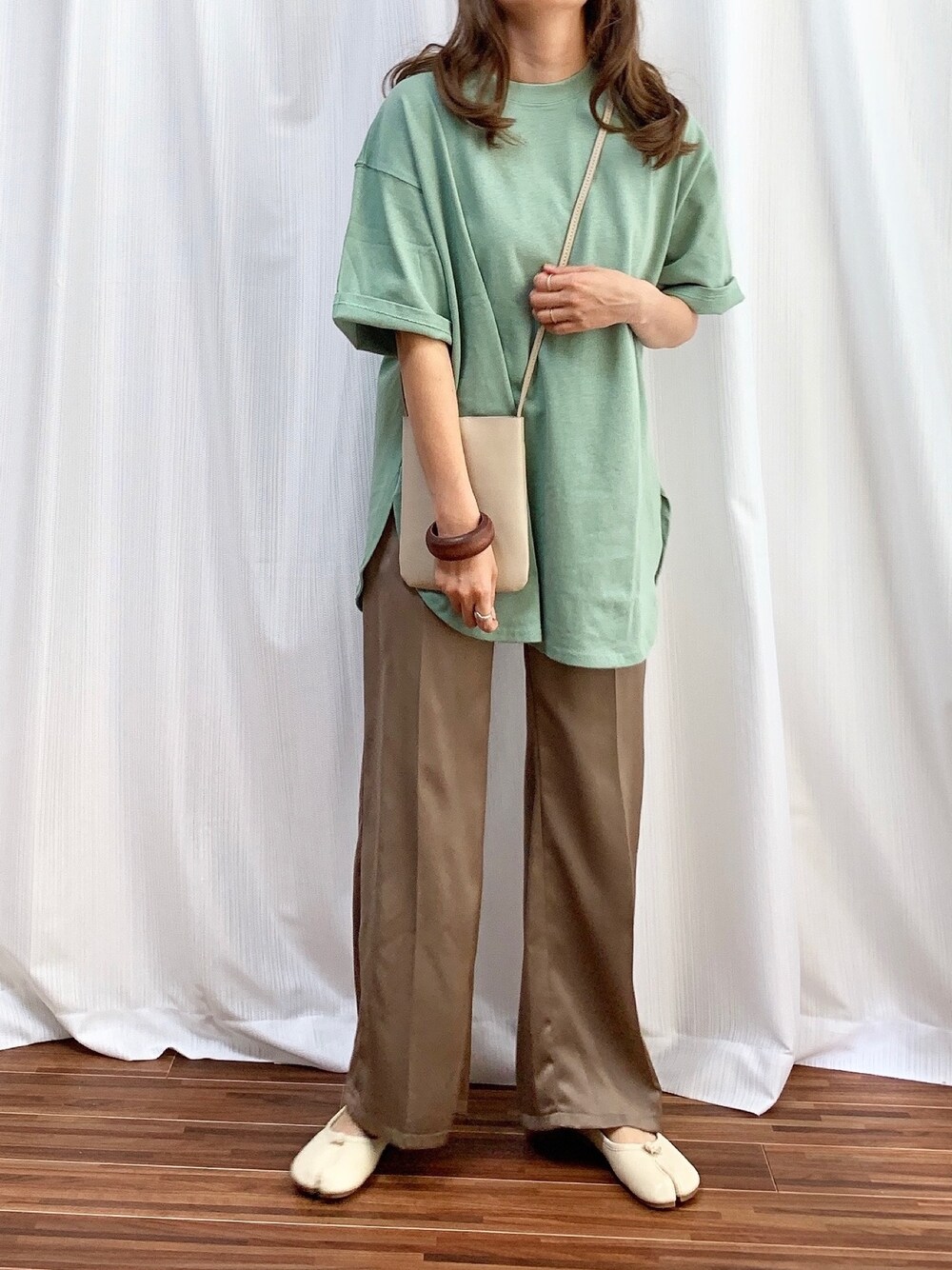グリーン系のTシャツ/カットソー、ホワイト系のショルダーバッグ、ブラウン系のパンツを着用したレディースの春コーディネートの1枚目の写真