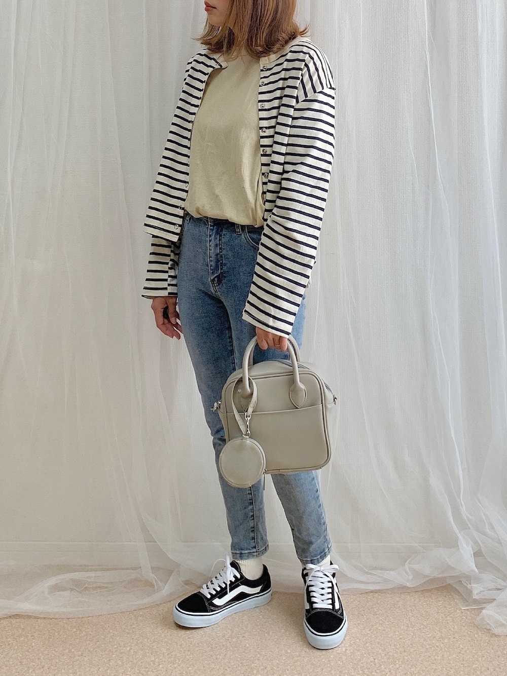 ホワイト系のカーディガン/ボレロ、ベージュ系のTシャツ/カットソー、ブルー系のデニムパンツを着用したレディースの春コーディネートの1枚目の写真