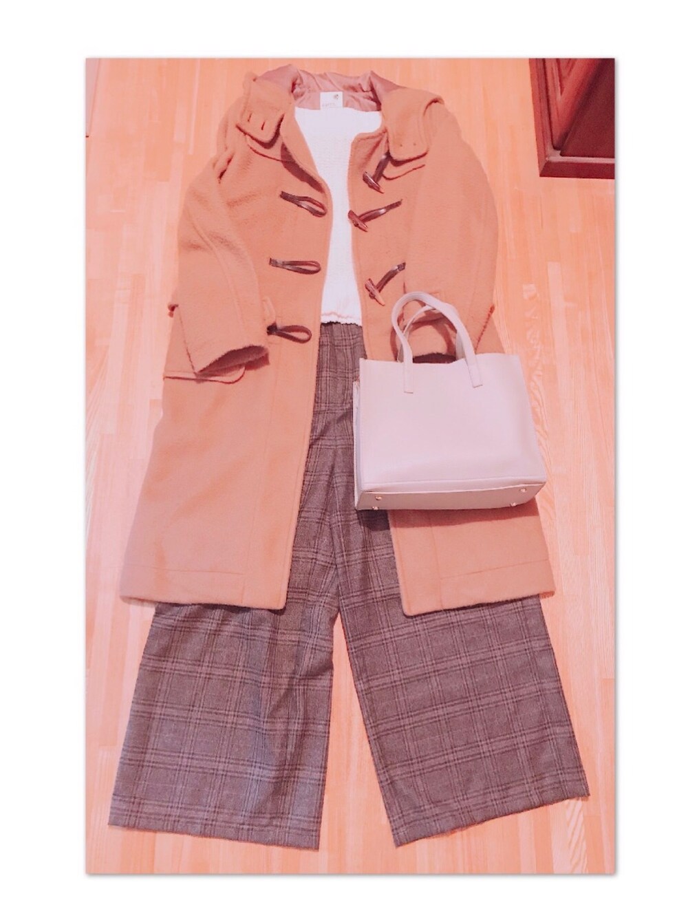 ブラウン系のダッフルコート、ホワイト系のニット/セーター、グレー系のパンツを着用したレディースの冬コーディネートの1枚目の写真