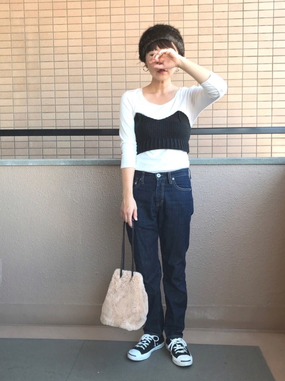 ブルー系のデニムパンツ、ブラック系のニット/セーター、ブラック系のスニーカーを着用したレディースの秋コーディネートの1枚目の写真