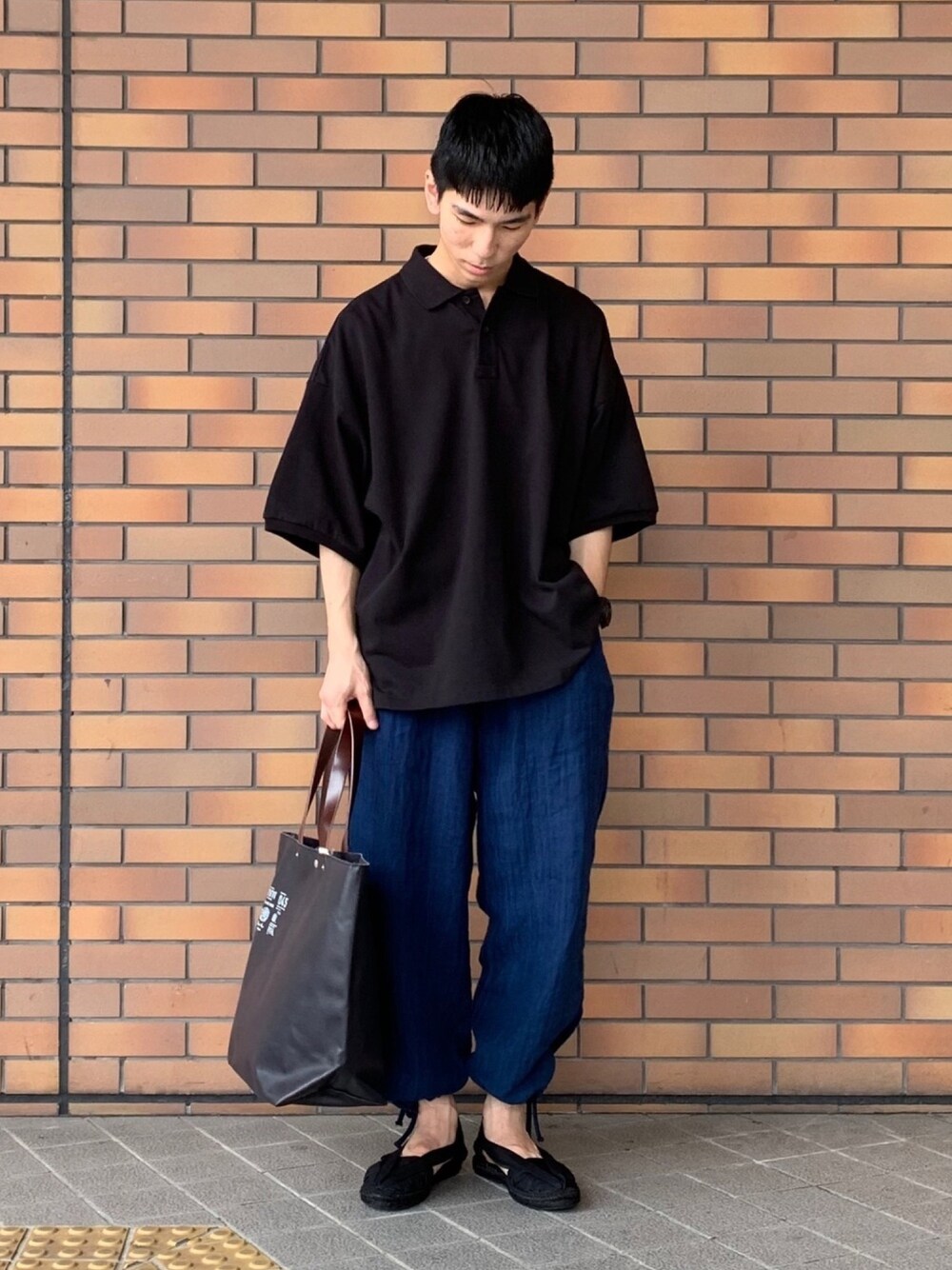 ブラック系のポロシャツ、ブルー系のその他パンツ、ブルー系のトートバッグを着用したメンズの夏コーディネートの1枚目の写真