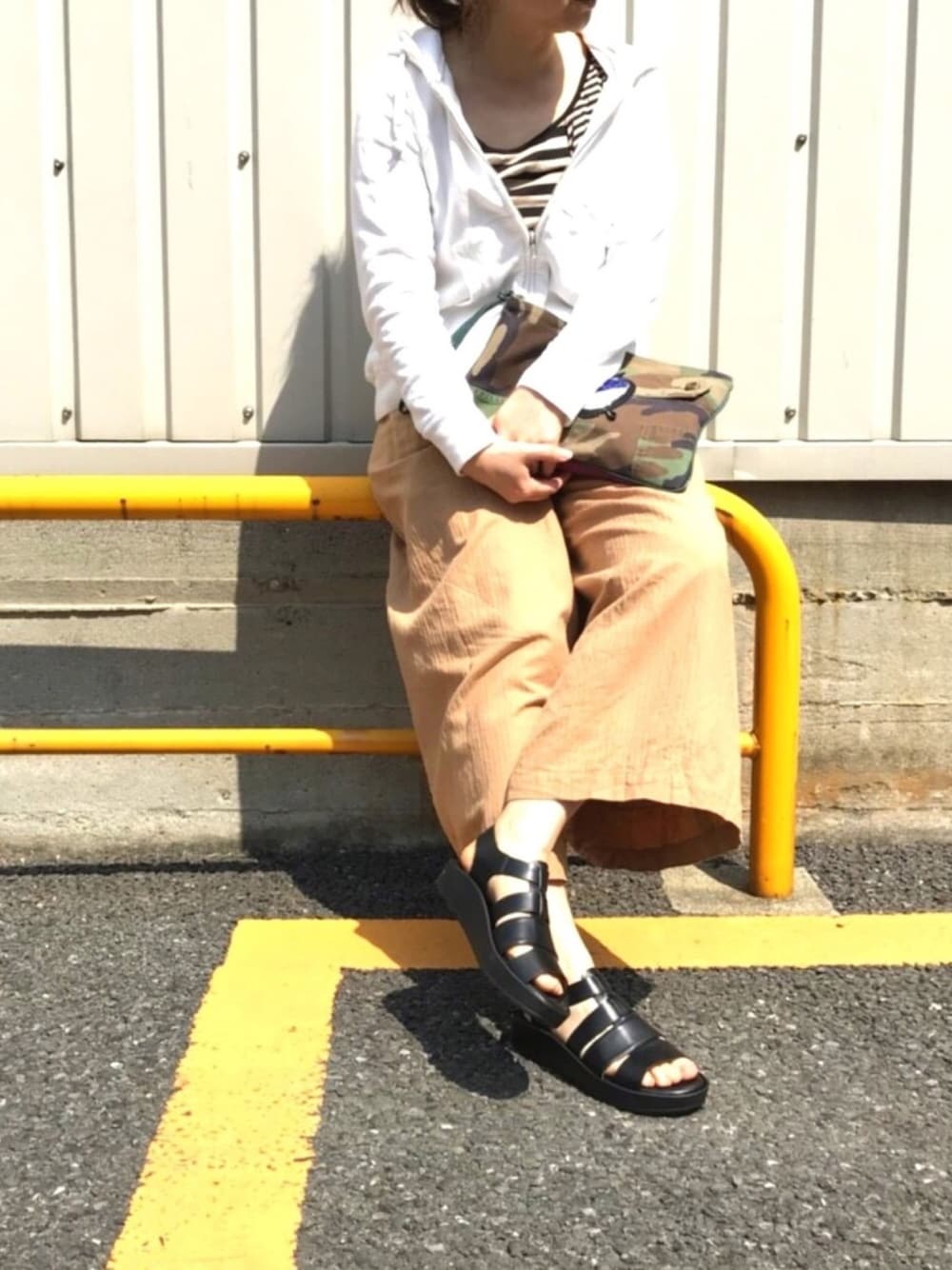 ベージュ系のその他パンツ、ホワイト系のパーカー、グリーン系のクラッチバッグを着用したレディースの春コーディネートの1枚目の写真