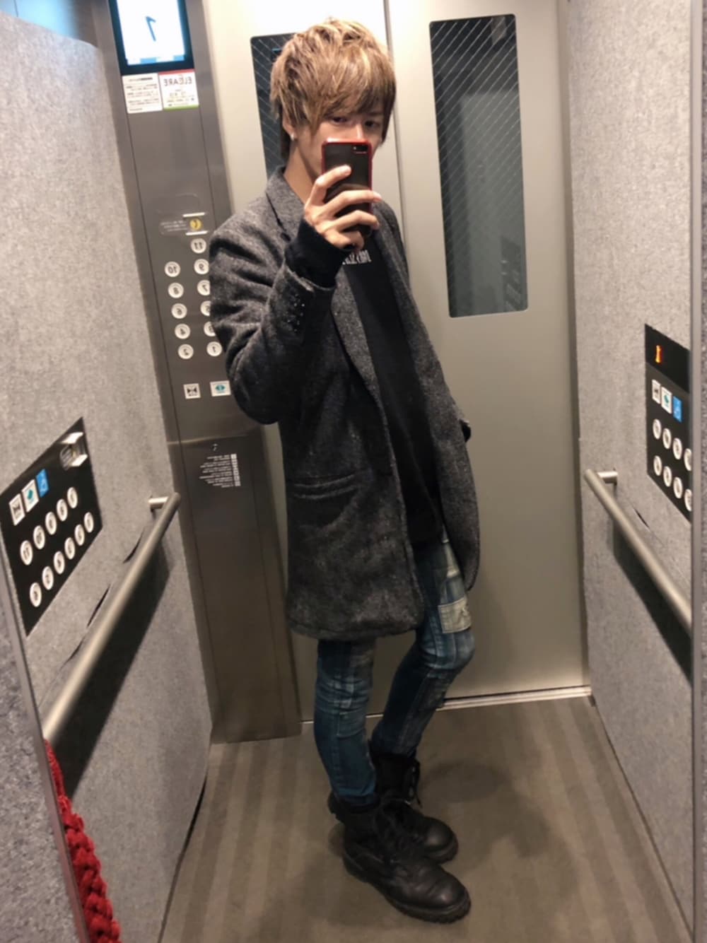 ブラック系のチェスターコート、ブラック系のニット/セーター、ブルー系のデニムパンツを着用したメンズの冬コーディネートの1枚目の写真