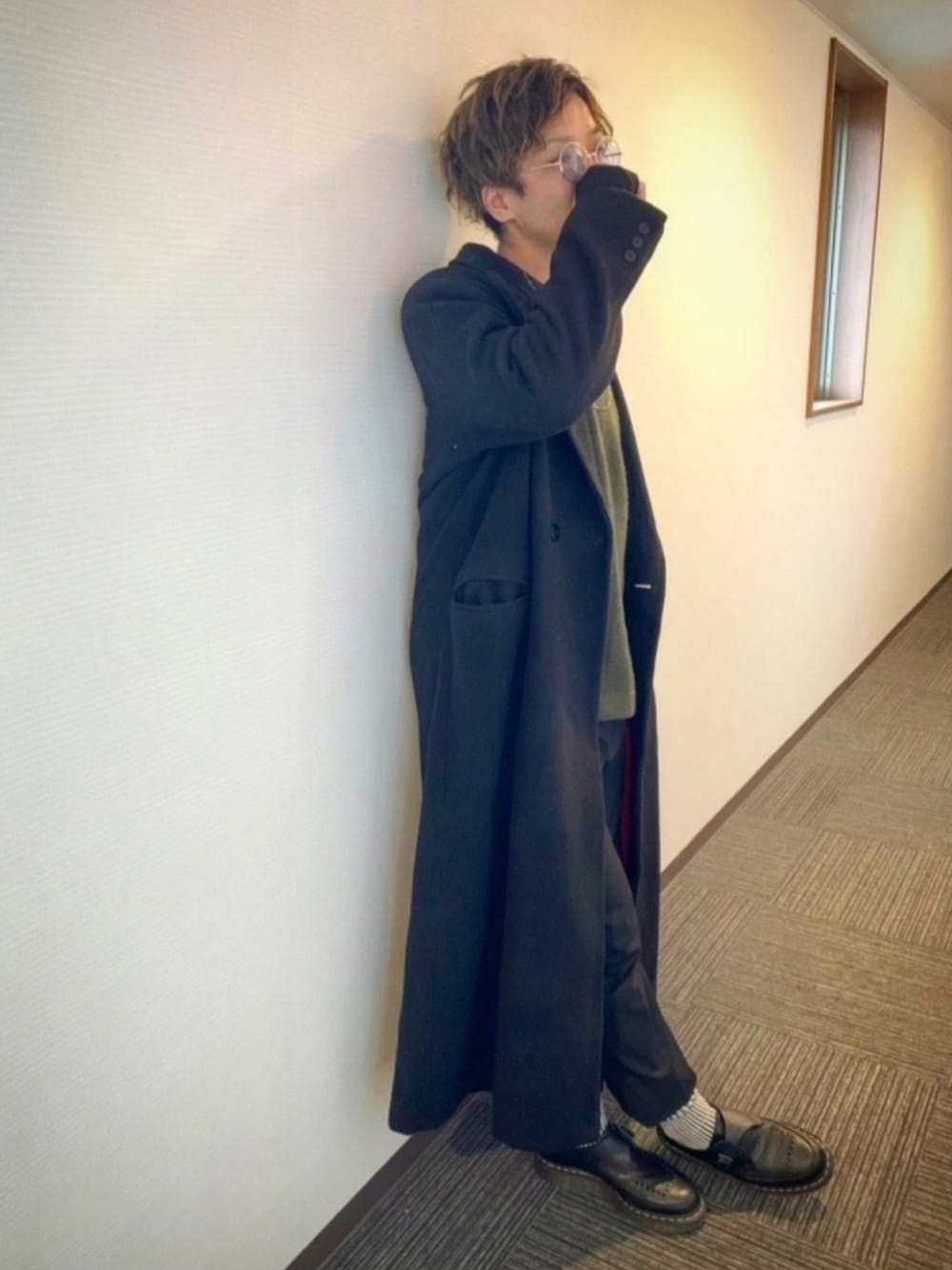 グリーン系のニット/セーター、ブラック系のスラックス、ブラック系のチェスターコートを着用したメンズの冬コーディネートの1枚目の写真