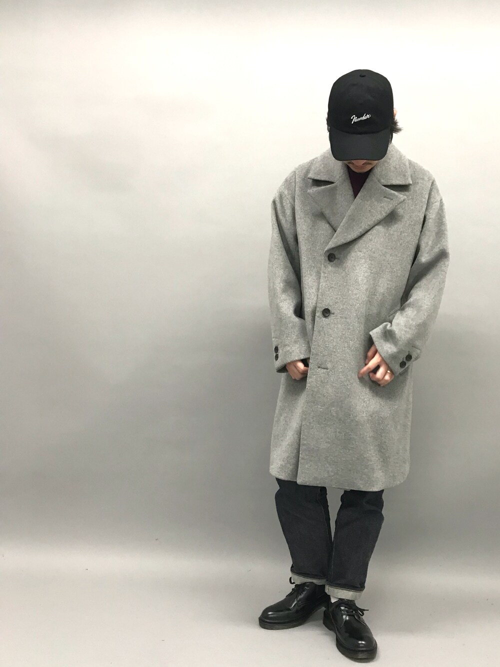 グレー系のチェスターコート、パープル系のニット/セーター、ブルー系のデニムパンツを着用したメンズの秋コーディネートの1枚目の写真