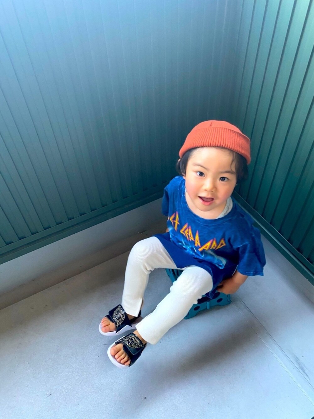 ホワイト系のパンツ、ブラック系のサンダル、オレンジ系のニットキャップ/ビーニーを着用したキッズの春コーディネートの1枚目の写真