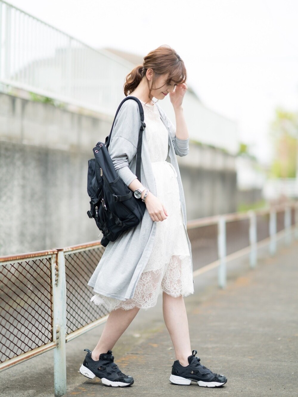 グレー系のカーディガン/ボレロ、ホワイト系のワンピース、ブラック系のバックパック/リュックを着用したレディースの春コーディネートの1枚目の写真
