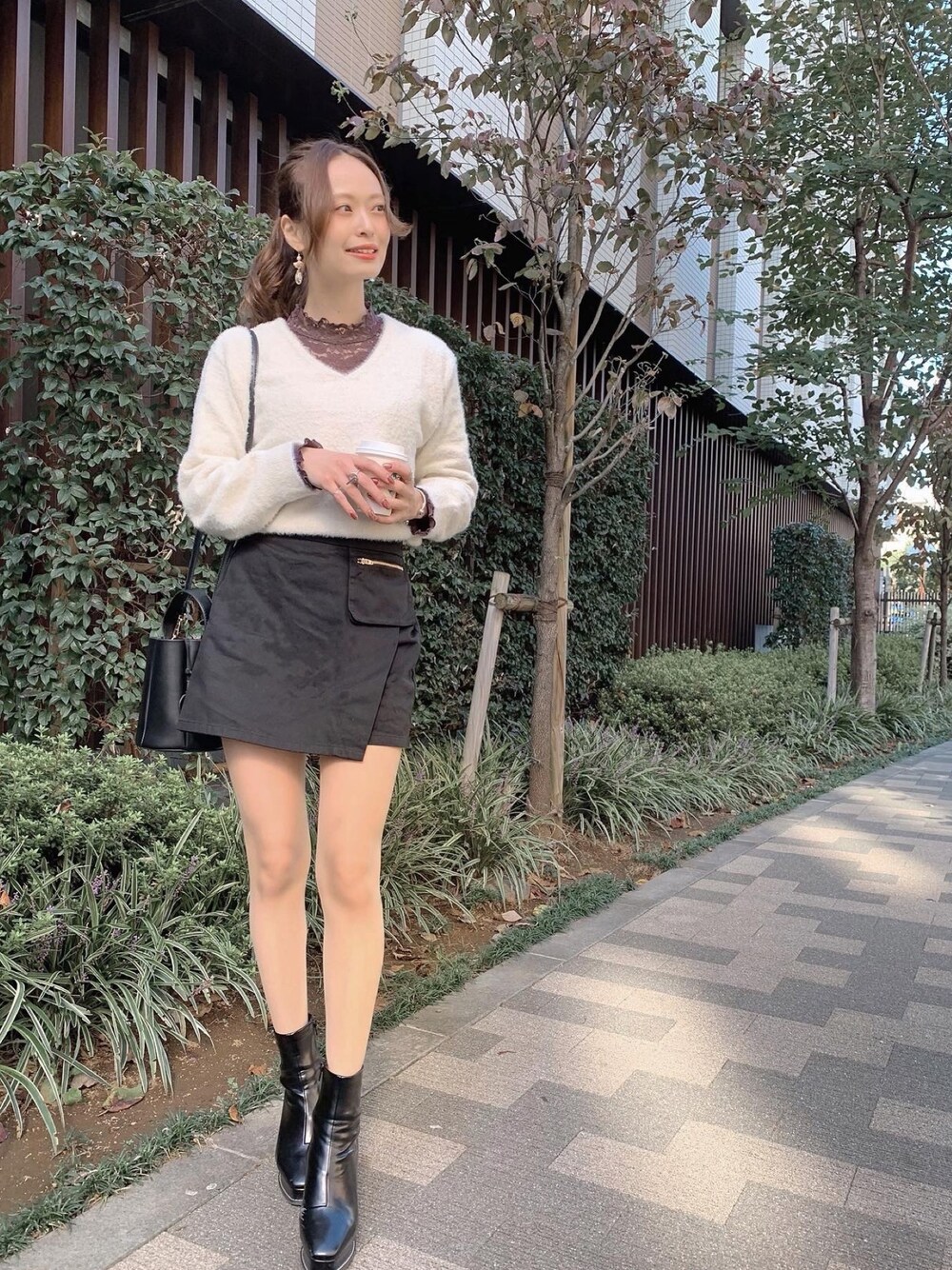 ブラック系のパンツ、ブラック系のブーツ、ホワイト系のニット/セーターを着用したレディースの冬コーディネートの1枚目の写真