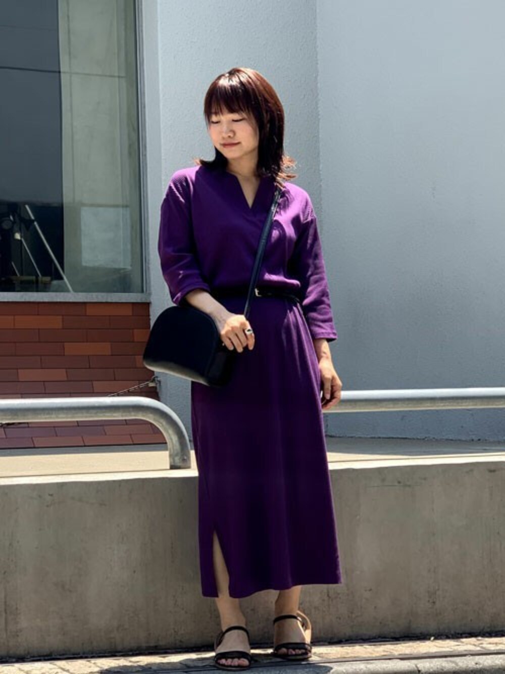 パープル系のワンピース、ブラック系のサンダル、ブラック系のショルダーバッグを着用したレディースの夏コーディネートの1枚目の写真