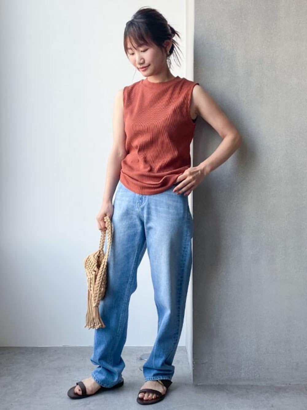 オレンジ系のタンクトップ、ブルー系のデニムパンツ、イエロー系のショルダーバッグを着用したレディースの夏コーディネートの1枚目の写真