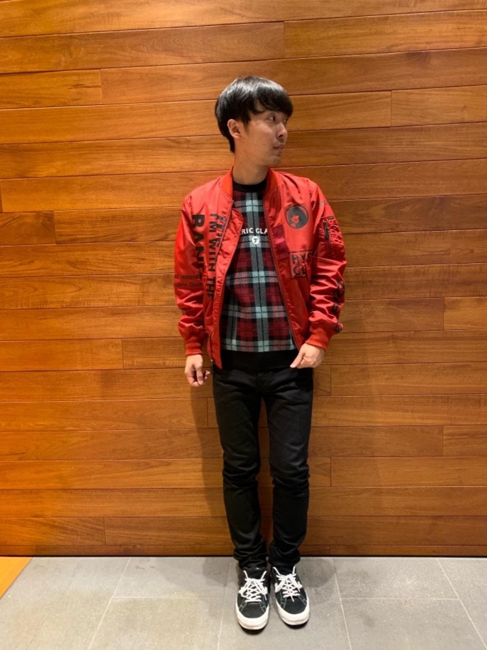 ブラック系のデニムパンツ、レッド系のミリタリージャケット、ブルー系のニット/セーターを着用したメンズの秋コーディネートの1枚目の写真