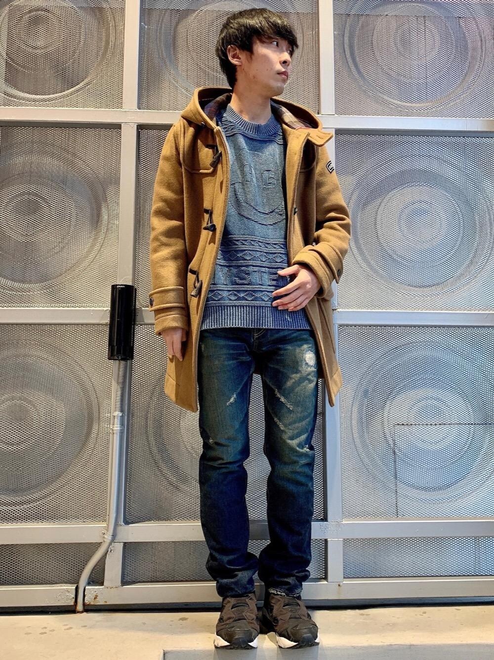 ブルー系のデニムパンツ、ベージュ系のダッフルコート、ブルー系のニット/セーターを着用したメンズの冬コーディネートの1枚目の写真