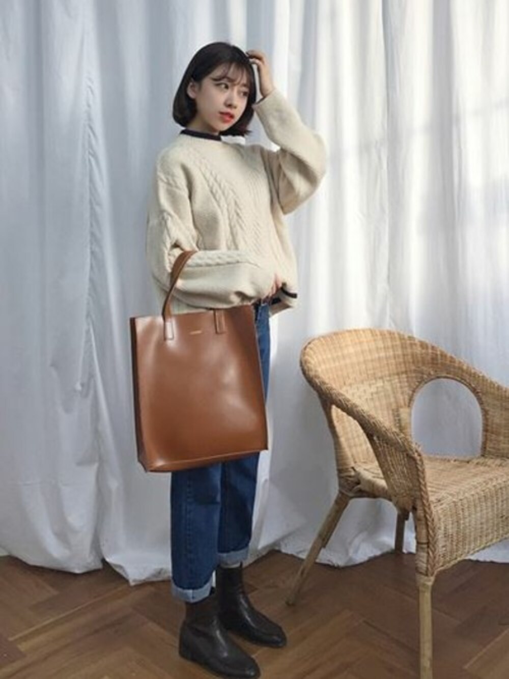 ホワイト系のニット/セーター、ブルー系のデニムパンツ、ブラウン系のトートバッグを着用したレディースの冬コーディネートの1枚目の写真