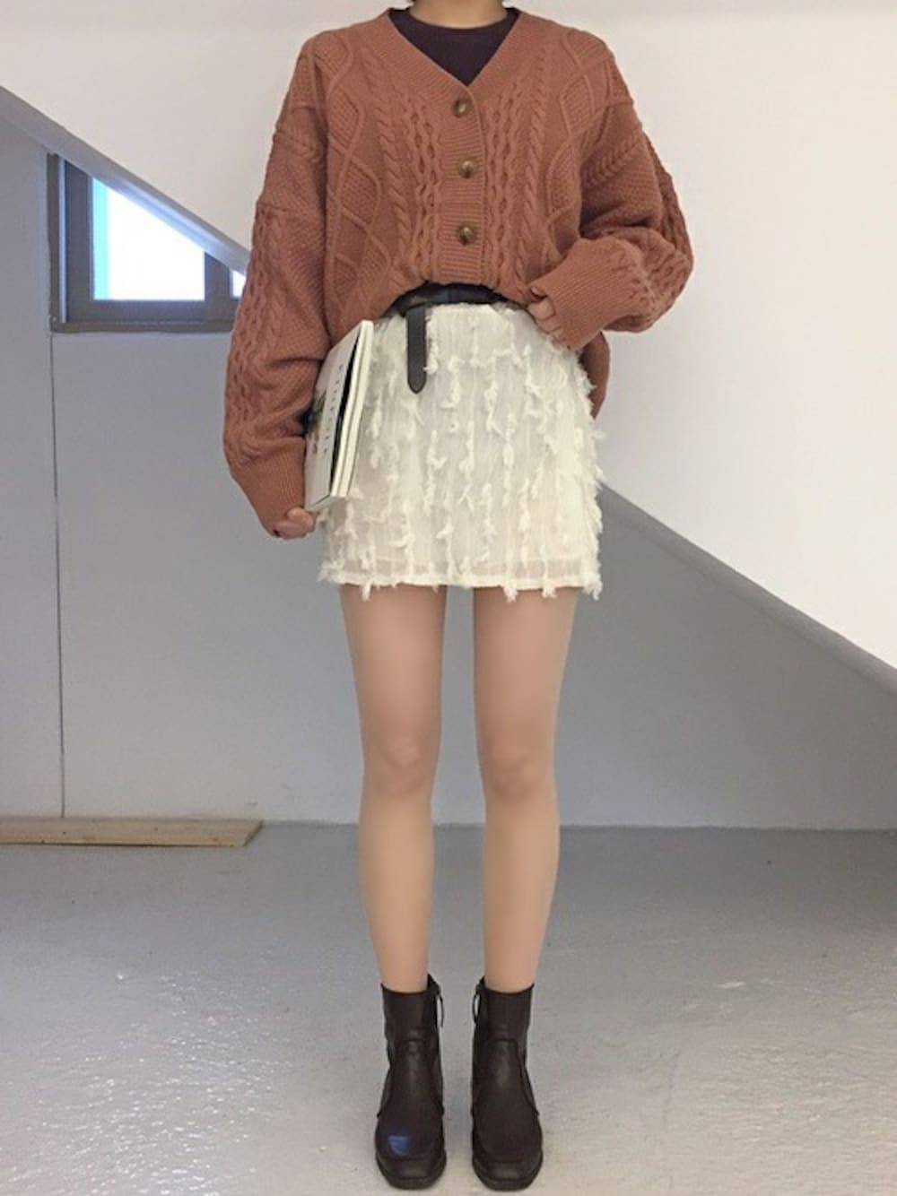 ピンク系のカーディガン/ボレロ、ホワイト系のスカート、ブラウン系のブーツを着用したレディースの冬コーディネートの1枚目の写真