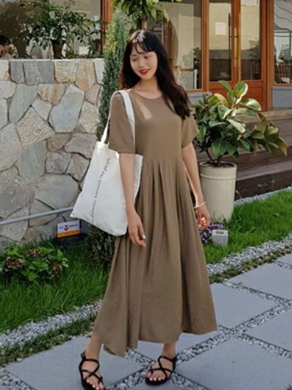 ブラウン系のワンピース、ブラック系のサンダル、ホワイト系のトートバッグを着用したレディースの夏コーディネートの1枚目の写真