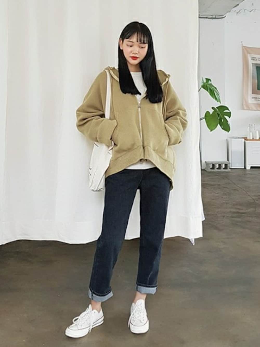 グリーン系のパーカー、ホワイト系のスウェット、ブラック系のデニムパンツを着用したレディースの秋コーディネートの1枚目の写真