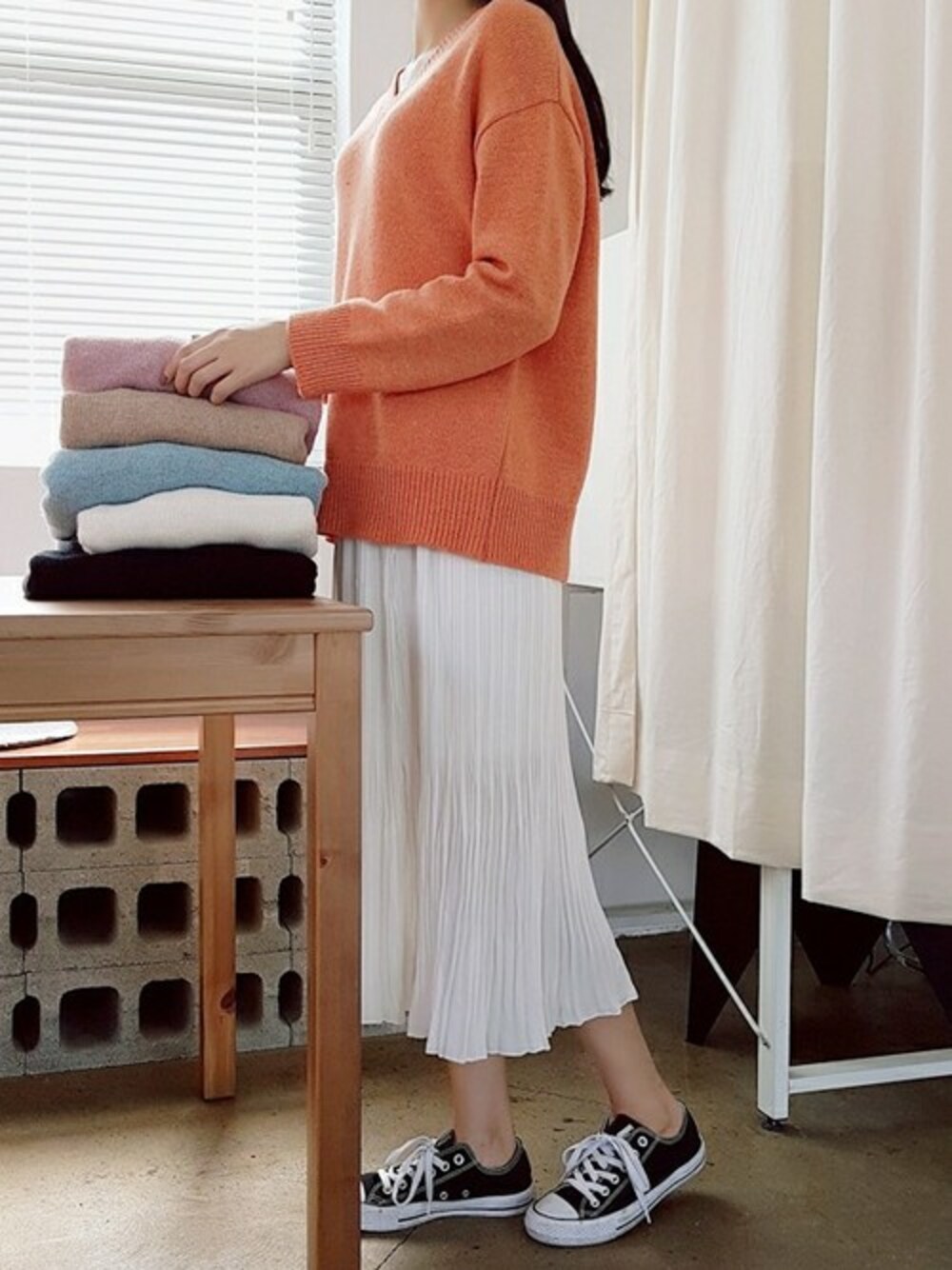 オレンジ系のニット/セーター、ホワイト系のスカートを着用したレディースの秋コーディネートの1枚目の写真