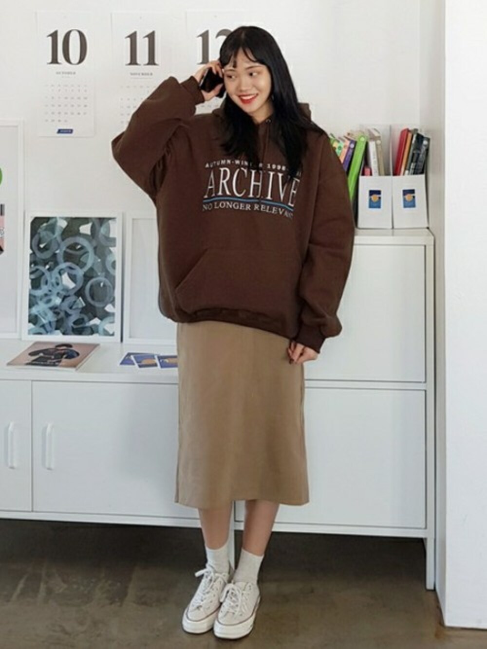 ブラウン系のパーカー、ベージュ系のスカートを着用したレディースの秋コーディネートの1枚目の写真
