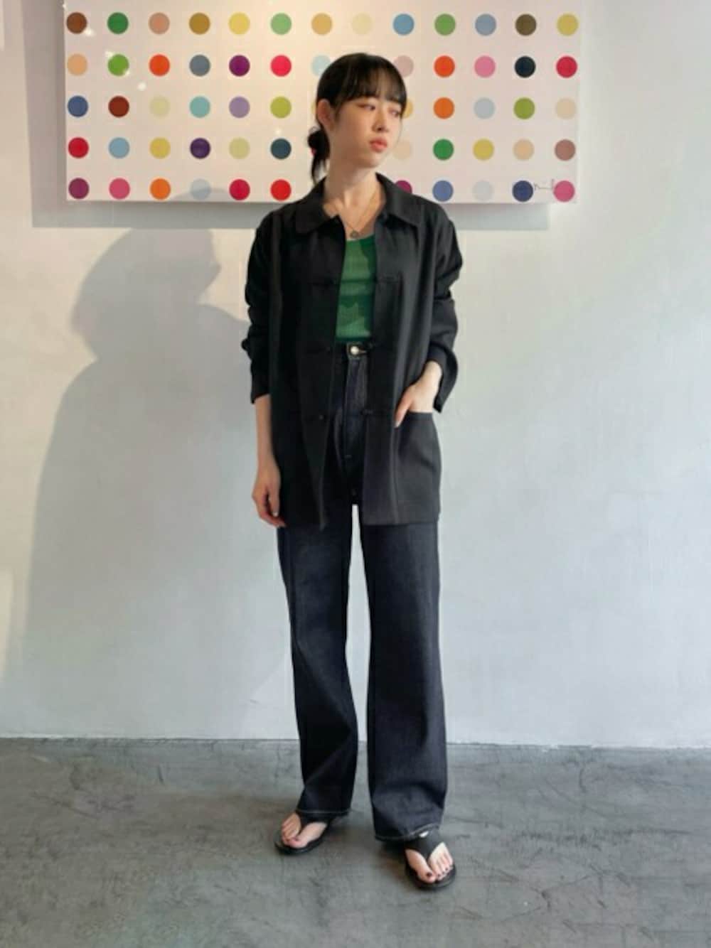 ブラック系のカバーオール、ブルー系のデニムパンツ、グリーン系のニット/セーターを着用したレディースの春コーディネートの1枚目の写真