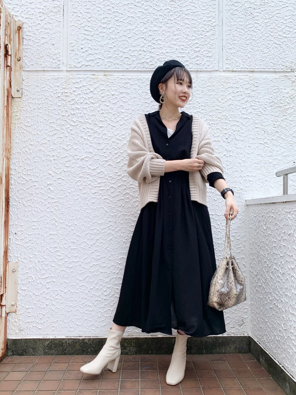 ブラック系のワンピース、ベージュ系のカーディガン/ボレロ、ブラック系のハンドバッグを着用したレディースの秋コーディネートの1枚目の写真