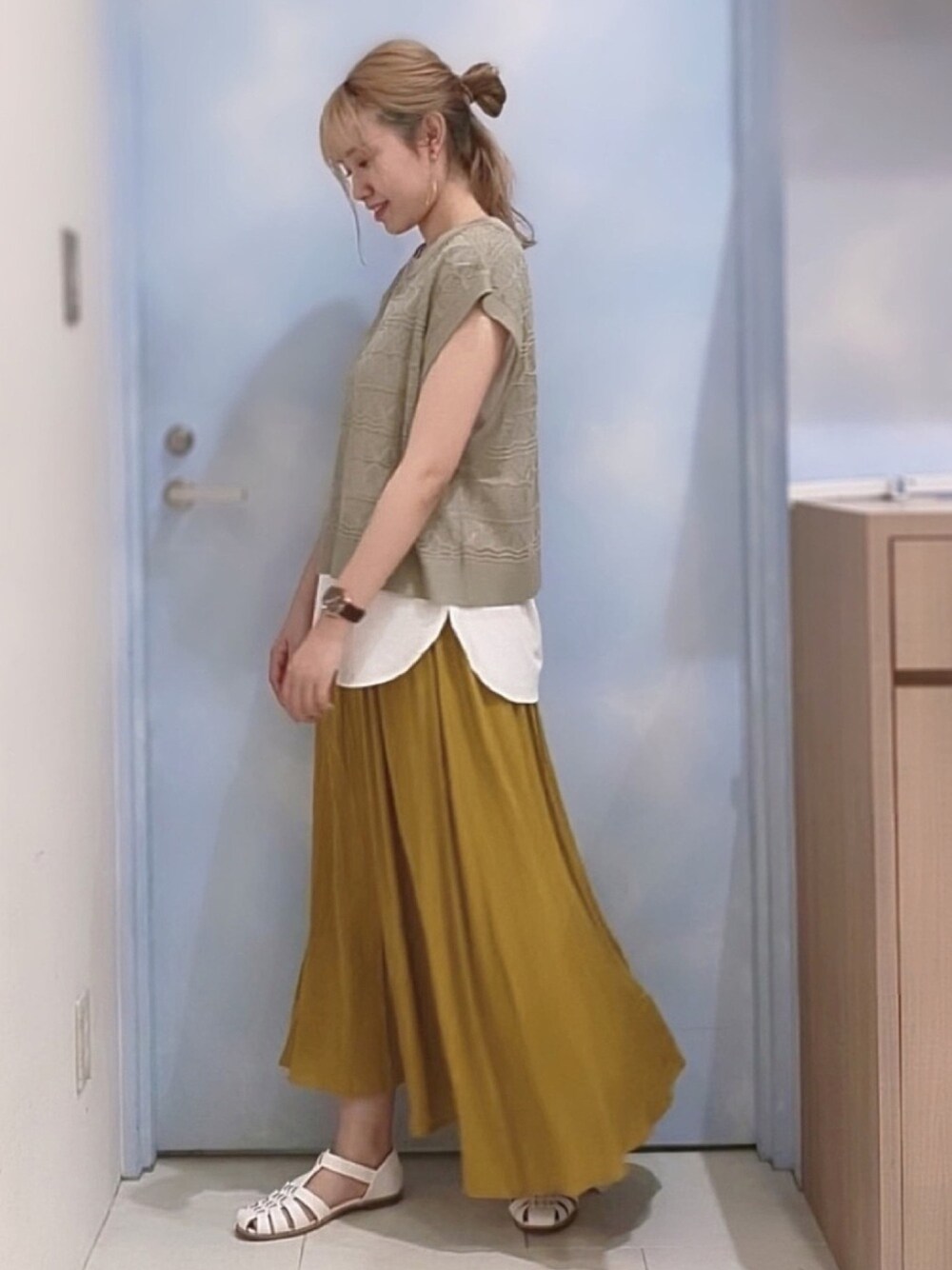 ベージュ系のTシャツ/カットソー、イエロー系のスカート、ホワイト系のサンダルを着用したレディースの春コーディネートの1枚目の写真