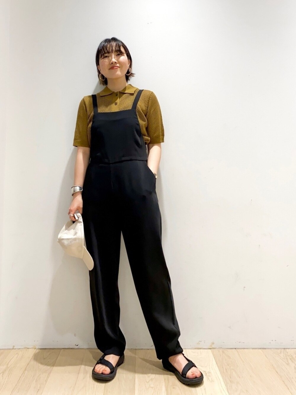 グリーン系のニット/セーター、ブラック系のサロペット/オーバーオール、ブラック系のサンダルを着用したレディースの春コーディネートの1枚目の写真