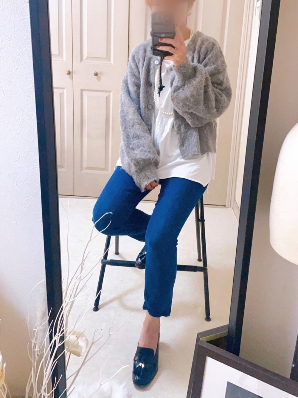 グレー系のカーディガン/ボレロ、ホワイト系のTシャツ/カットソー、ブラック系のデニムパンツを着用したレディースの秋コーディネートの1枚目の写真