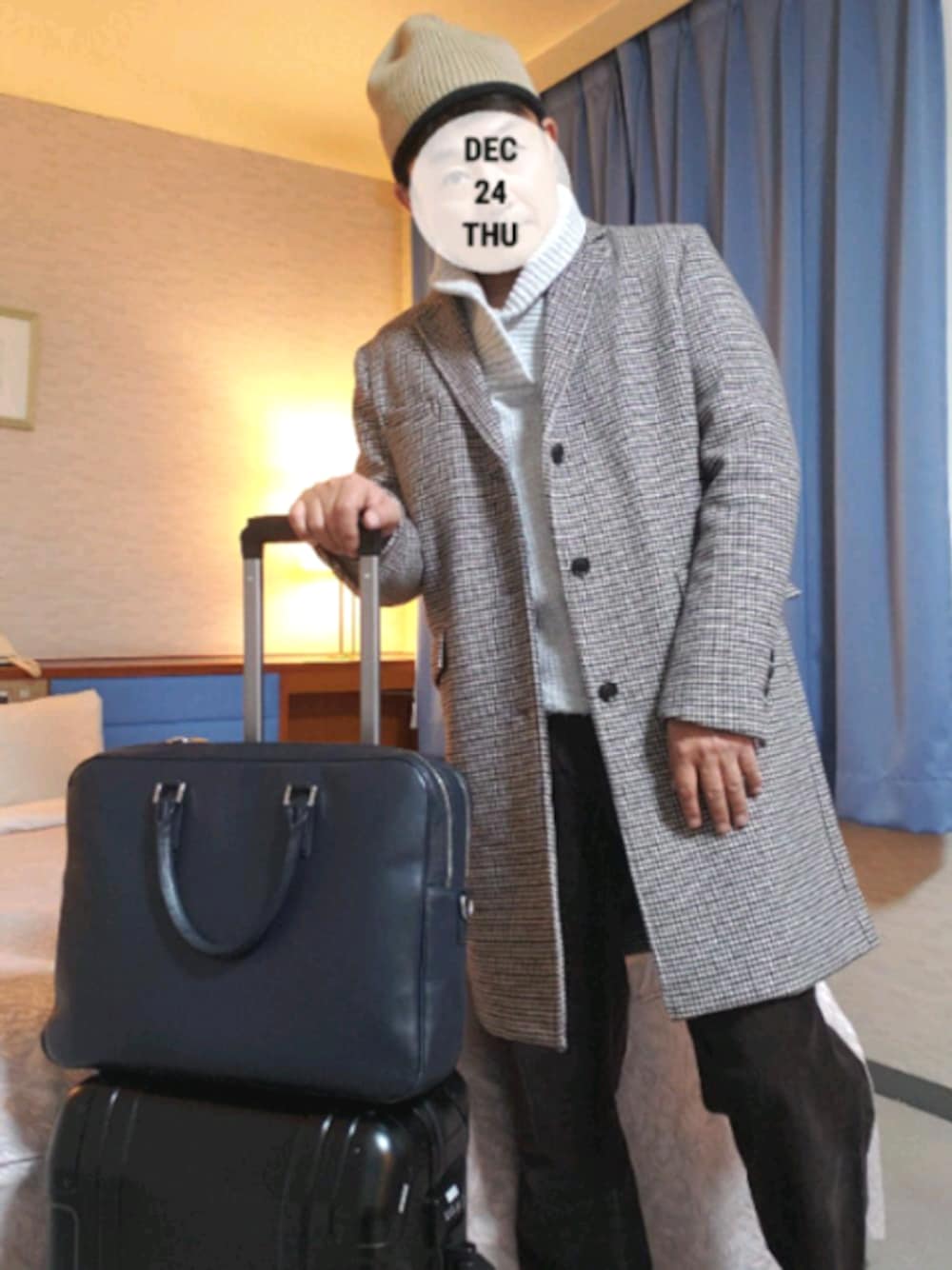 ベージュ系のチェスターコート、ブラウン系のその他パンツ、ブルー系のビジネスバッグを着用したメンズの冬コーディネートの1枚目の写真