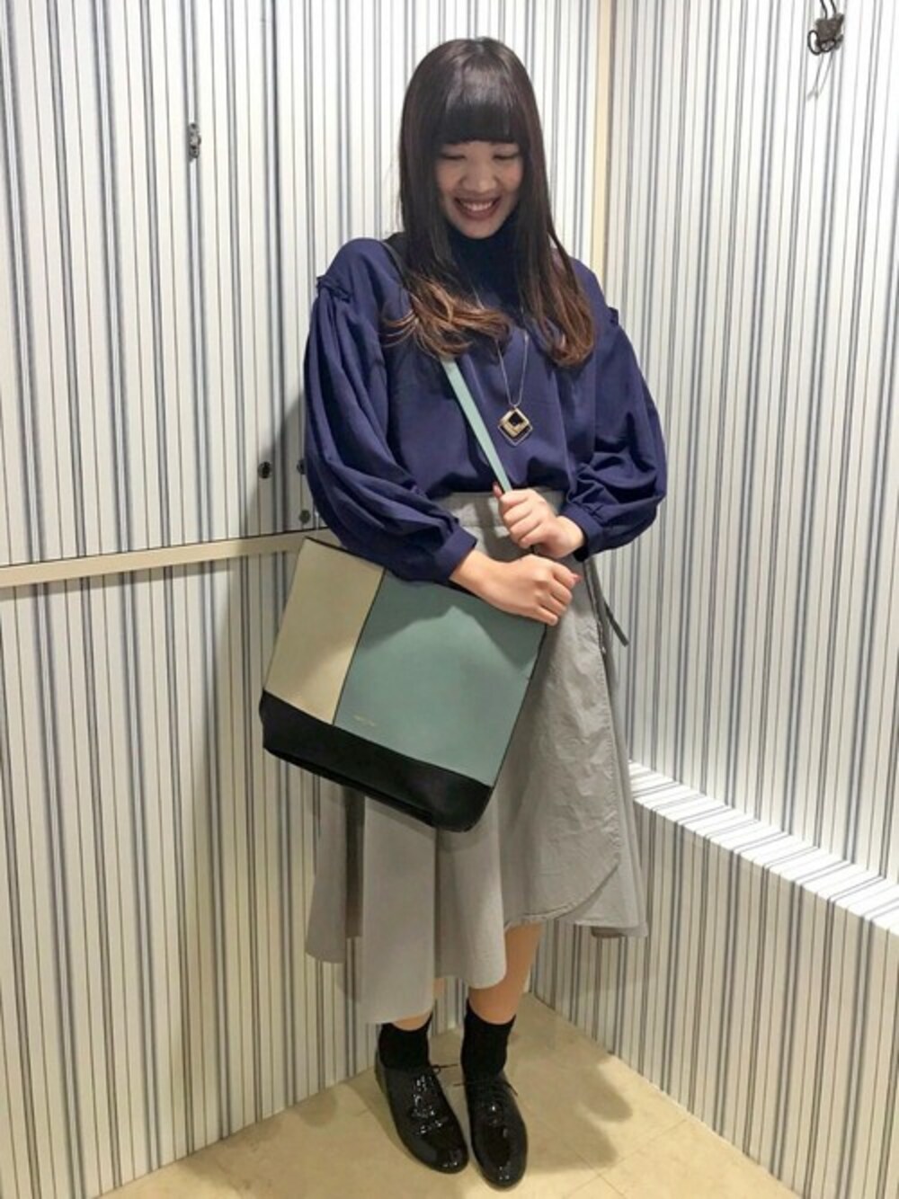 ホワイト系のトートバッグ、ブルー系のシャツ/ブラウス、グレー系のスカートを着用したレディースの冬コーディネートの1枚目の写真