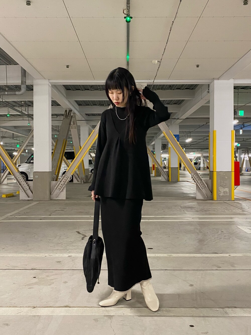 ブラック系のワンピース、イエロー系のショルダーバッグ、ブラック系のブーツを着用したレディースの冬コーディネートの1枚目の写真