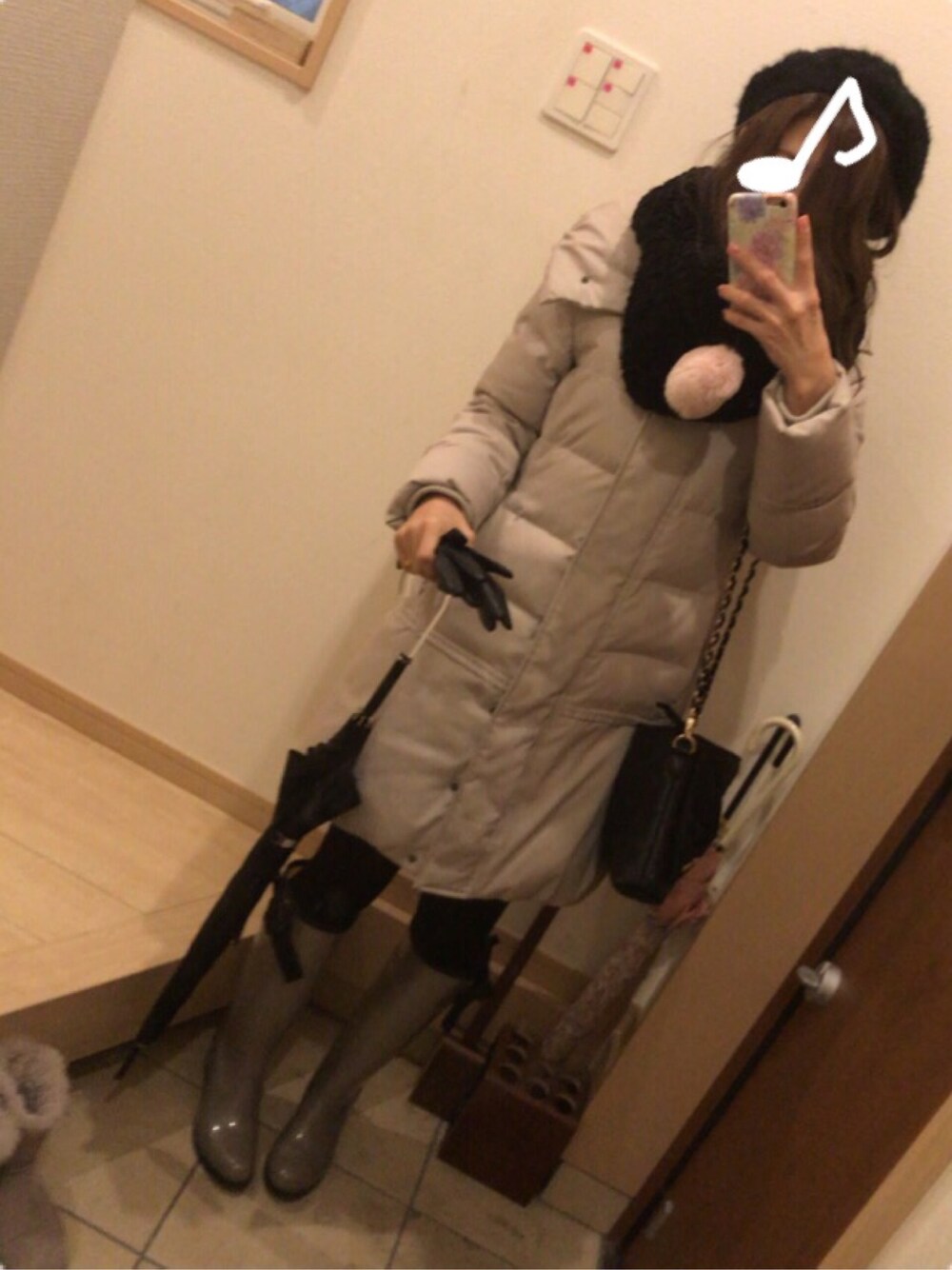 ベージュ系のレインシューズ、ブラック系のショルダーバッグ、ベージュ系のダウンジャケット/コートを着用したレディースの冬コーディネートの1枚目の写真