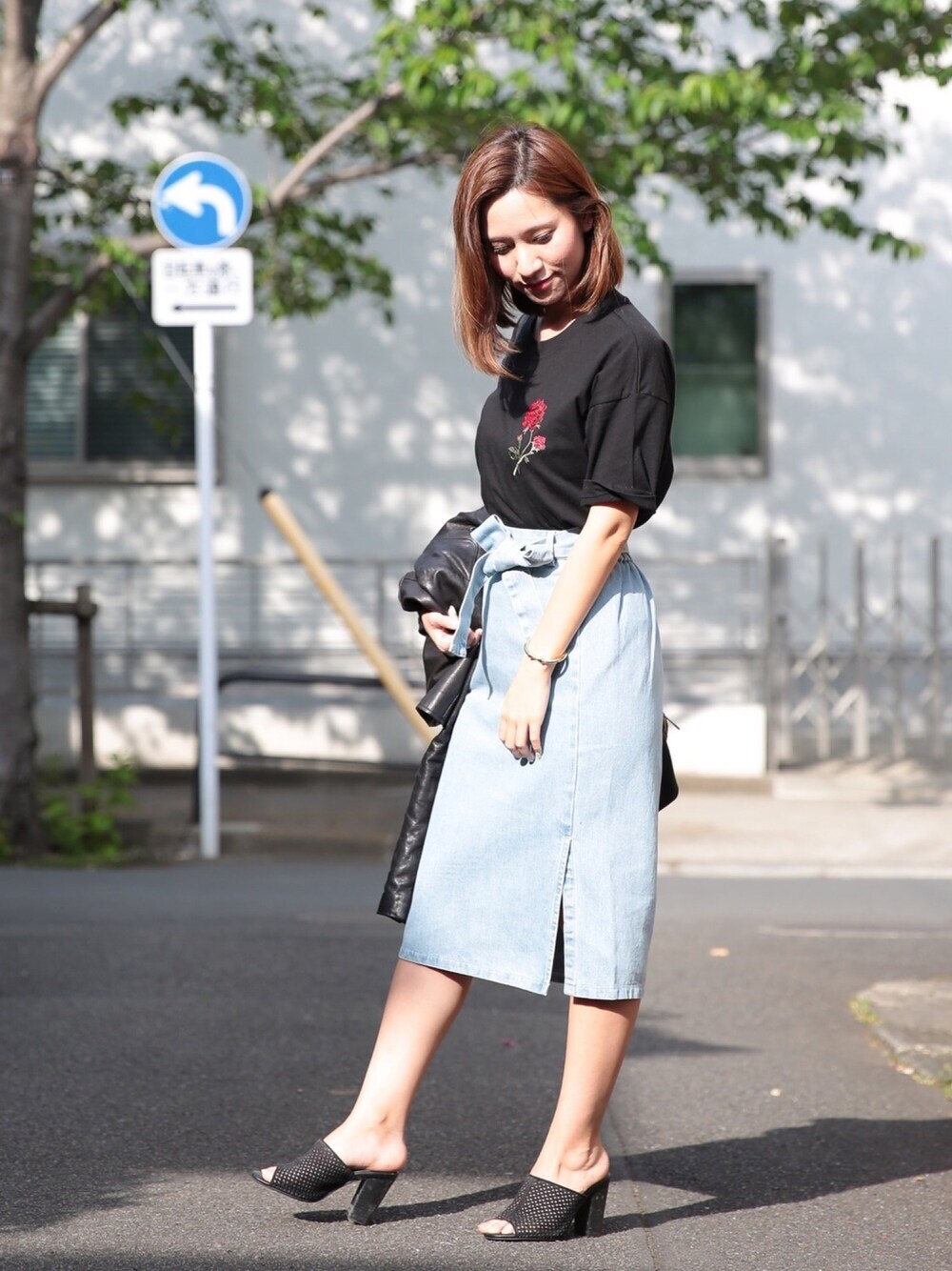 ブラック系のTシャツ/カットソー、ブルー系のデニムスカート、ブラック系のサンダルを着用したレディースの春コーディネートの1枚目の写真