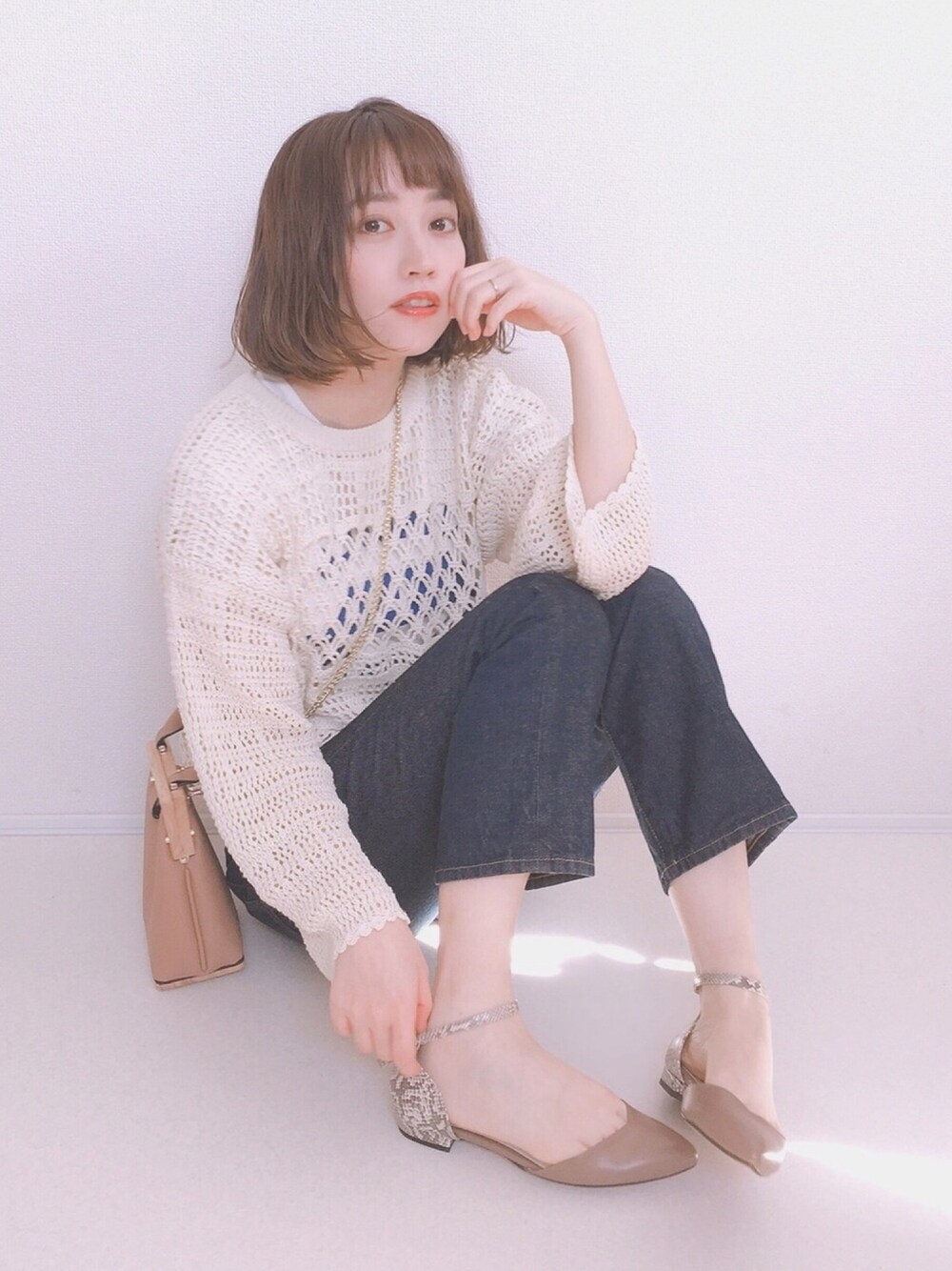 ホワイト系のニット/セーター、ブルー系のデニムパンツ、ベージュ系のパンプスを着用したレディースの冬コーディネートの1枚目の写真