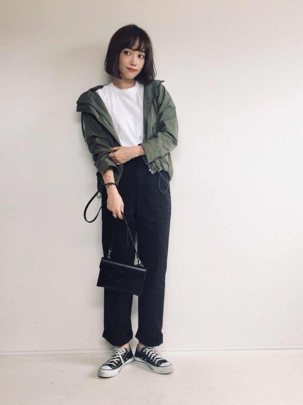 グリーン系のマウンテンパーカー、ホワイト系のTシャツ/カットソー、ブラック系のチノパンツを着用したレディースの秋コーディネートの1枚目の写真