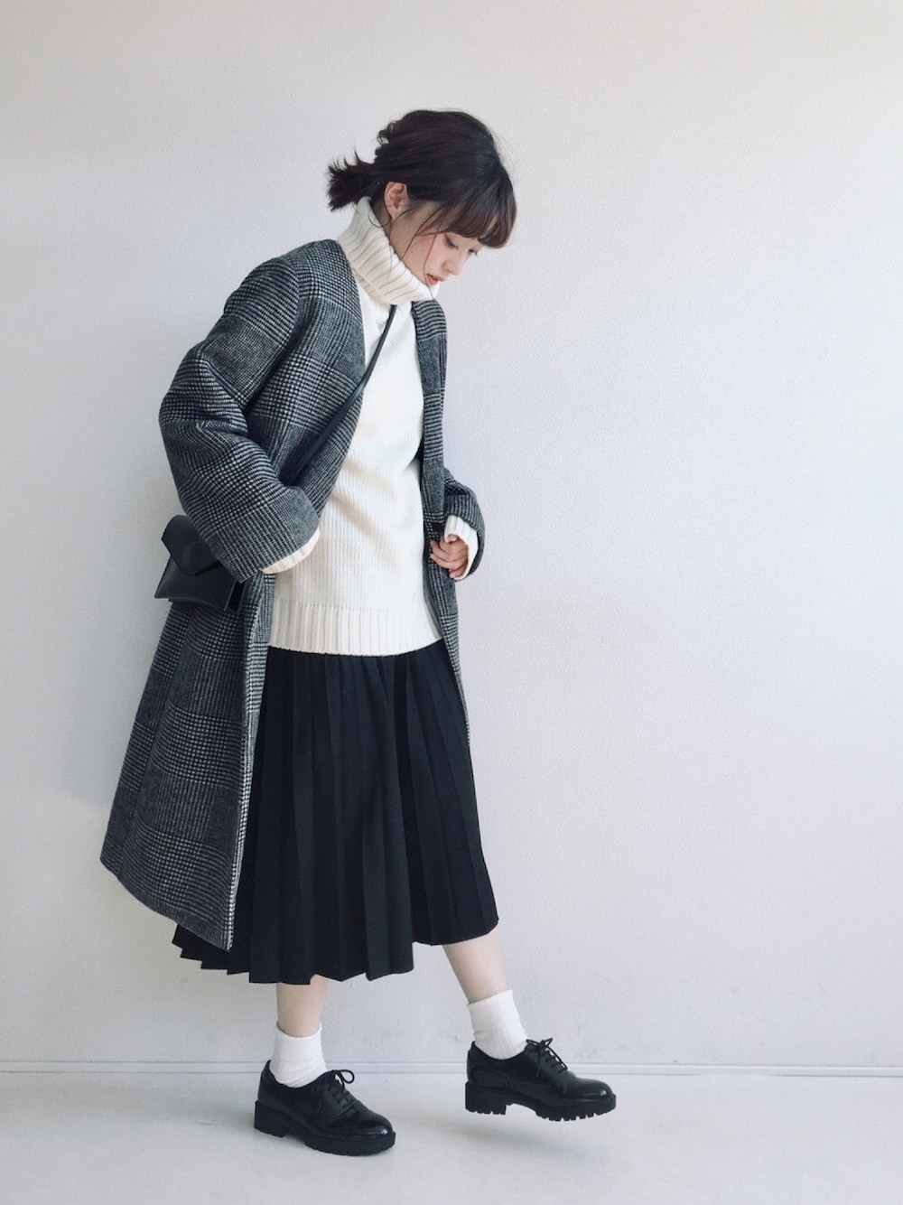 ホワイト系のニット/セーター、ブラック系のスカート、ブラック系のドレスシューズを着用したレディースの秋コーディネートの1枚目の写真