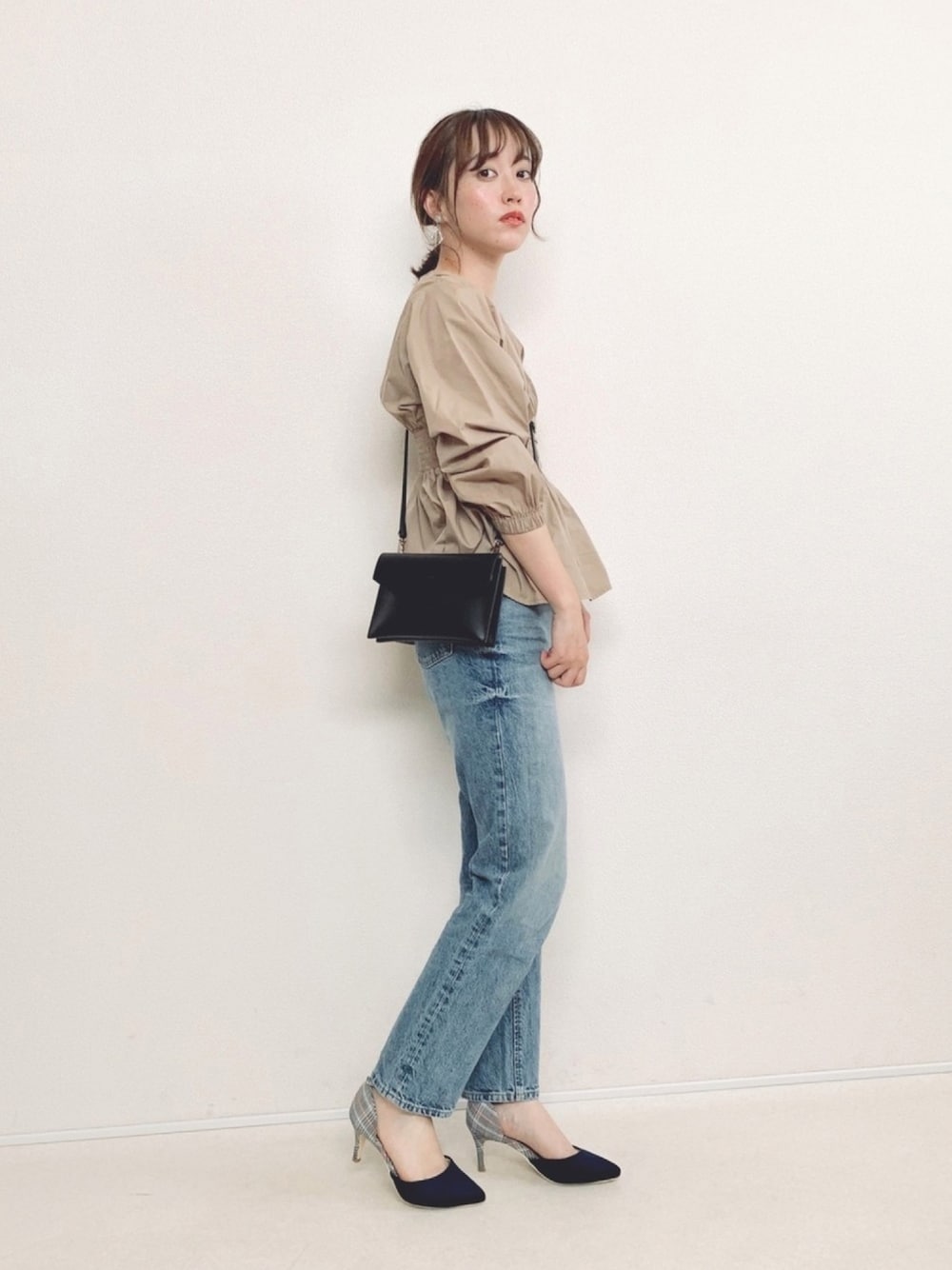 ベージュ系のシャツ/ブラウス、ブルー系のデニムパンツ、ブラック系のショルダーバッグを着用したレディースの春コーディネートの1枚目の写真