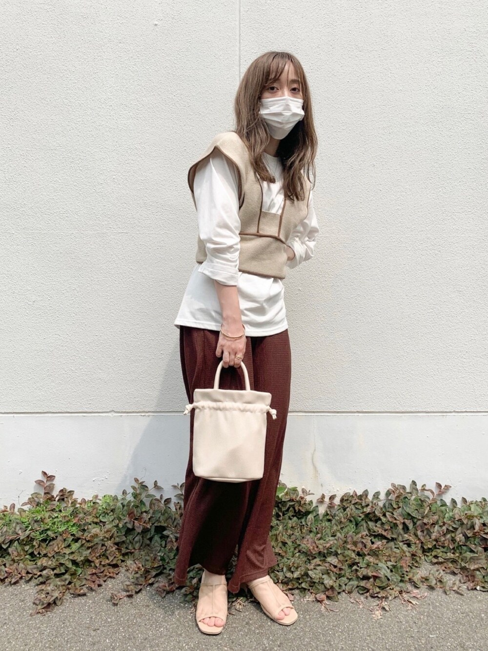 ベージュ系のベスト、ブラウン系のパンツ、ベージュ系のサンダルを着用したレディースの夏コーディネートの1枚目の写真