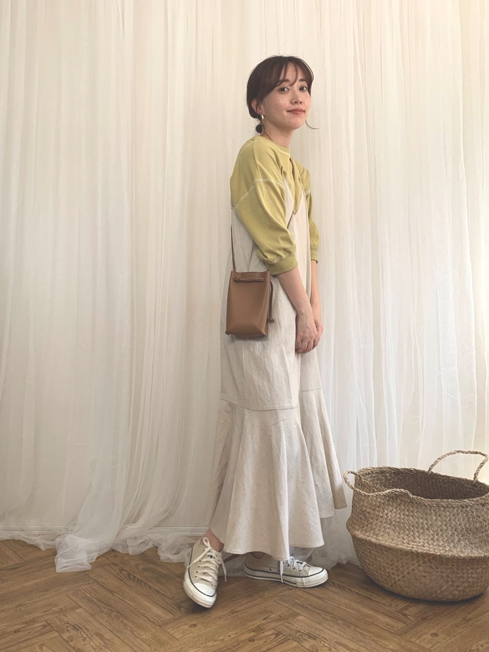 ベージュ系のワンピース、グリーン系のTシャツ/カットソーを着用したレディースの春コーディネートの1枚目の写真