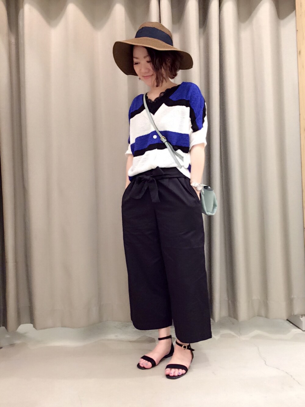 ブラック系のタンクトップ、ブルー系のカーディガン/ボレロ、グリーン系のショルダーバッグを着用したレディースの春コーディネートの1枚目の写真