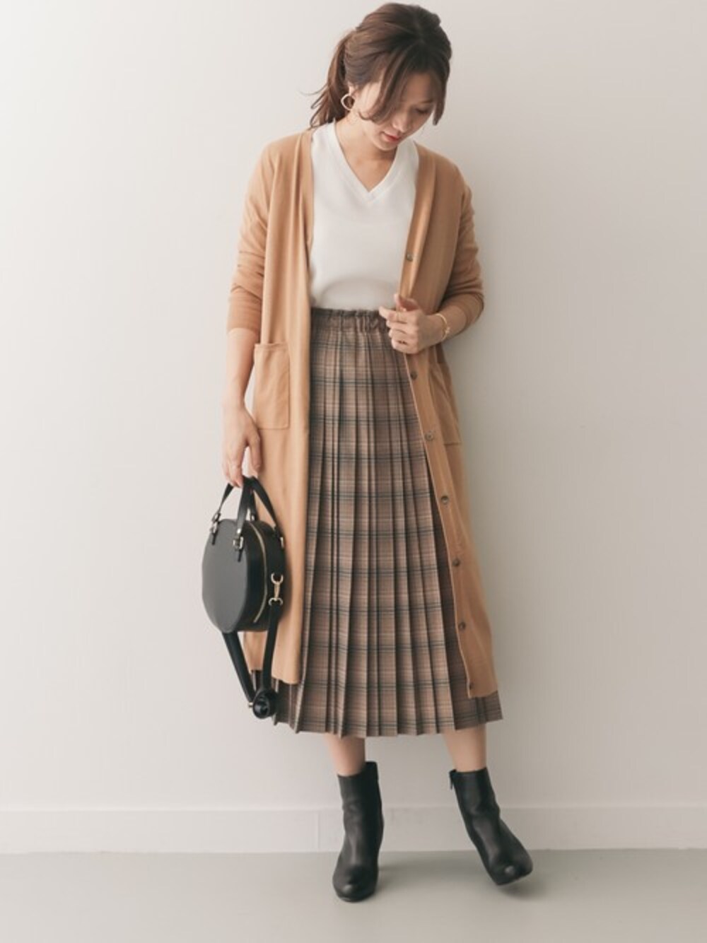 ベージュ系のカーディガン/ボレロ、ホワイト系のTシャツ/カットソー、ブラウン系のスカートを着用したレディースの秋コーディネートの1枚目の写真