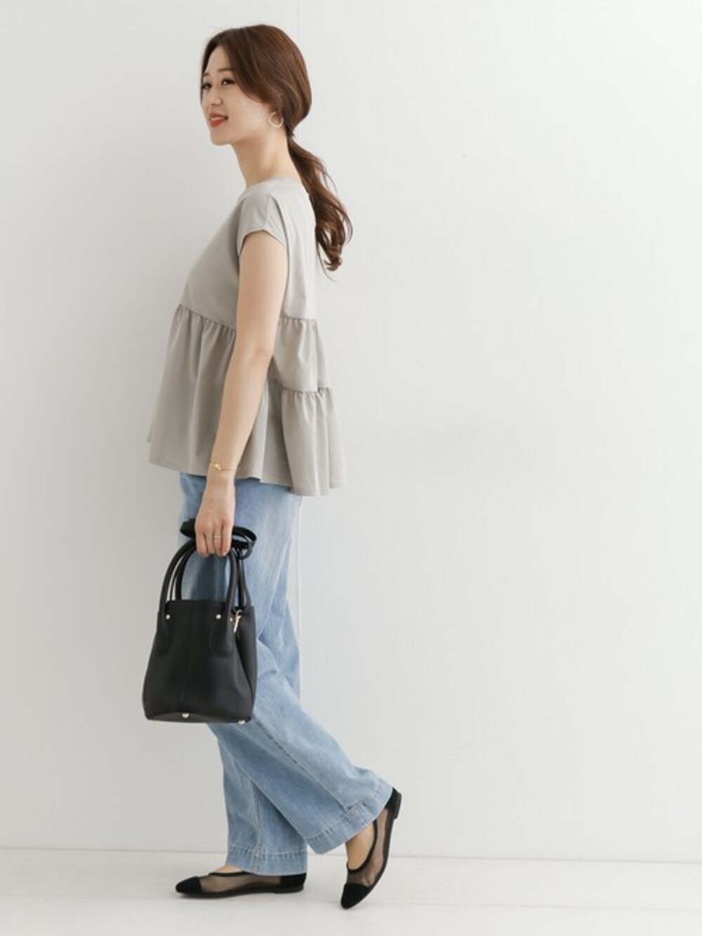 グレー系のTシャツ/カットソー、ブルー系のデニムパンツ、ブラック系のパンプスを着用したレディースの春コーディネートの1枚目の写真