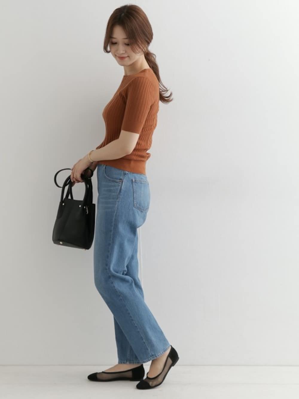 イエロー系のニット/セーター、ブルー系のデニムパンツ、ブラック系のパンプスを着用したレディースの春コーディネートの1枚目の写真