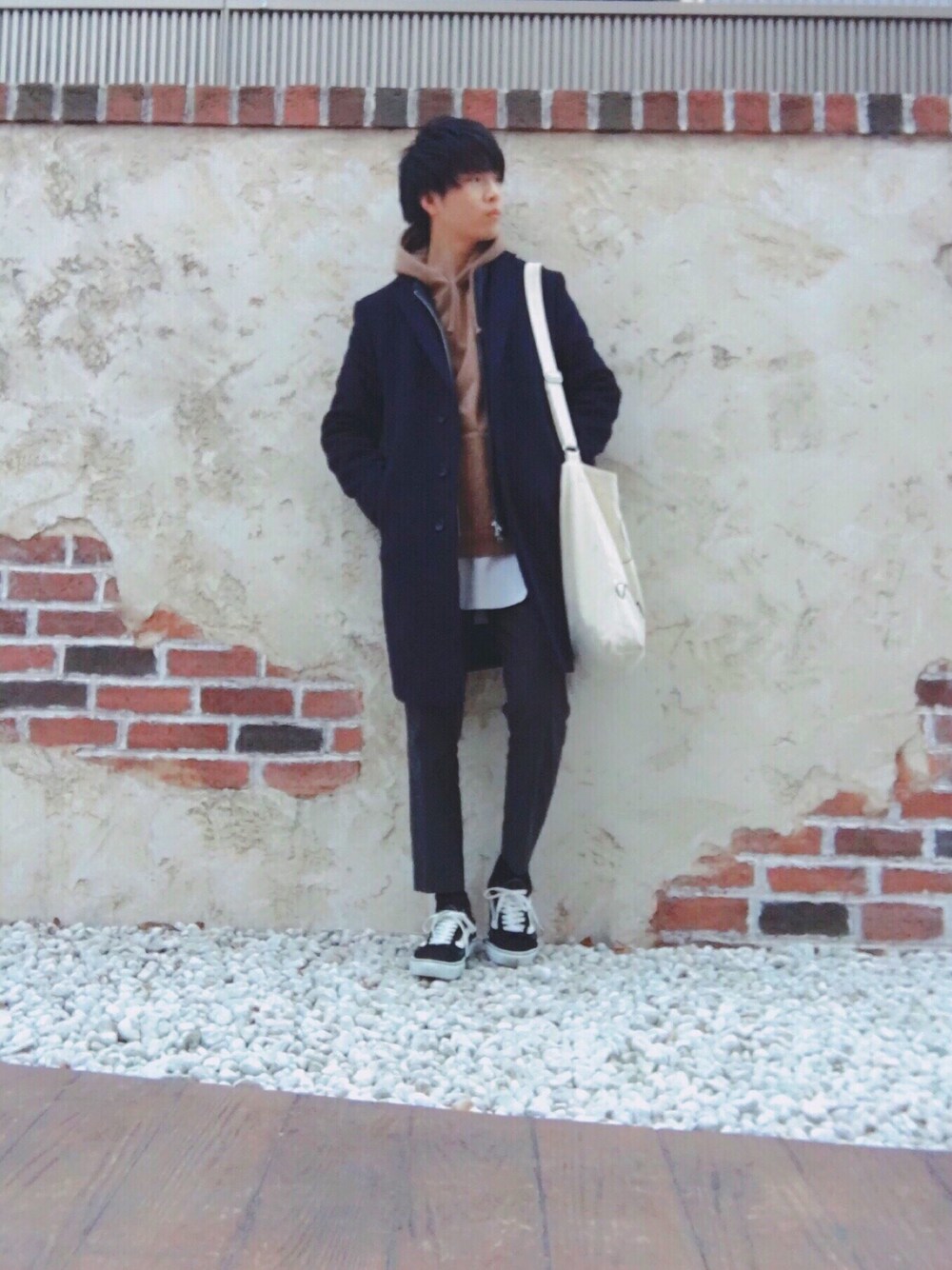 イエロー系のパーカー、ブルー系のチェスターコート、ブラック系のライダースジャケットを着用したメンズの冬コーディネートの1枚目の写真