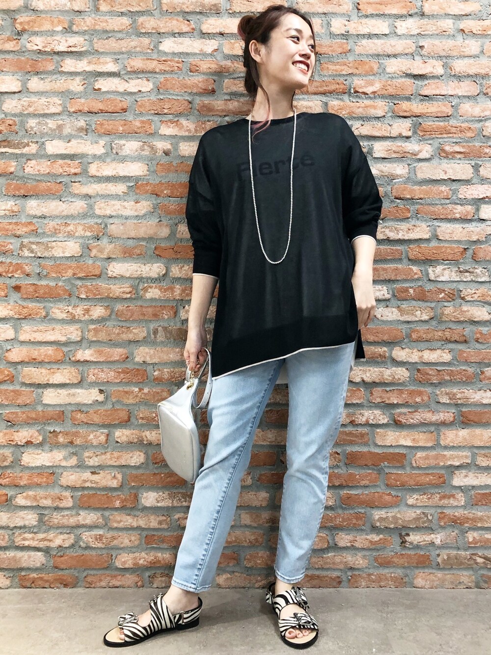 ブラック系のニット/セーター、ホワイト系のTシャツ/カットソー、ブルー系のデニムパンツを着用したレディースの夏コーディネートの1枚目の写真