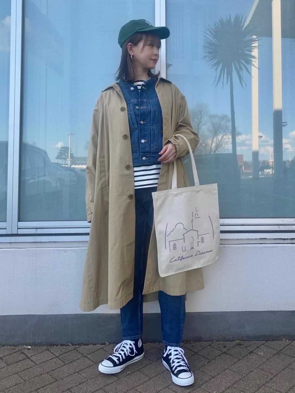 ブルー系のデニムパンツ、ベージュ系のステンカラーコート、ブルー系のデニムジャケットを着用したレディースの冬コーディネートの1枚目の写真