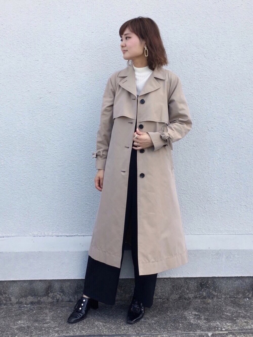 ベージュ系のトレンチコートを着用したレディースの秋コーディネートの1枚目の写真