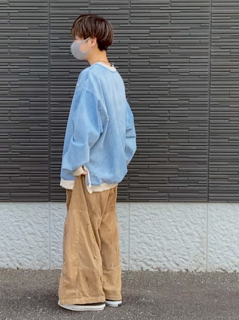 ブルー系のトップス、ベージュ系のパンツ、ブラック系のスニーカーを着用したレディースの春コーディネートの1枚目の写真